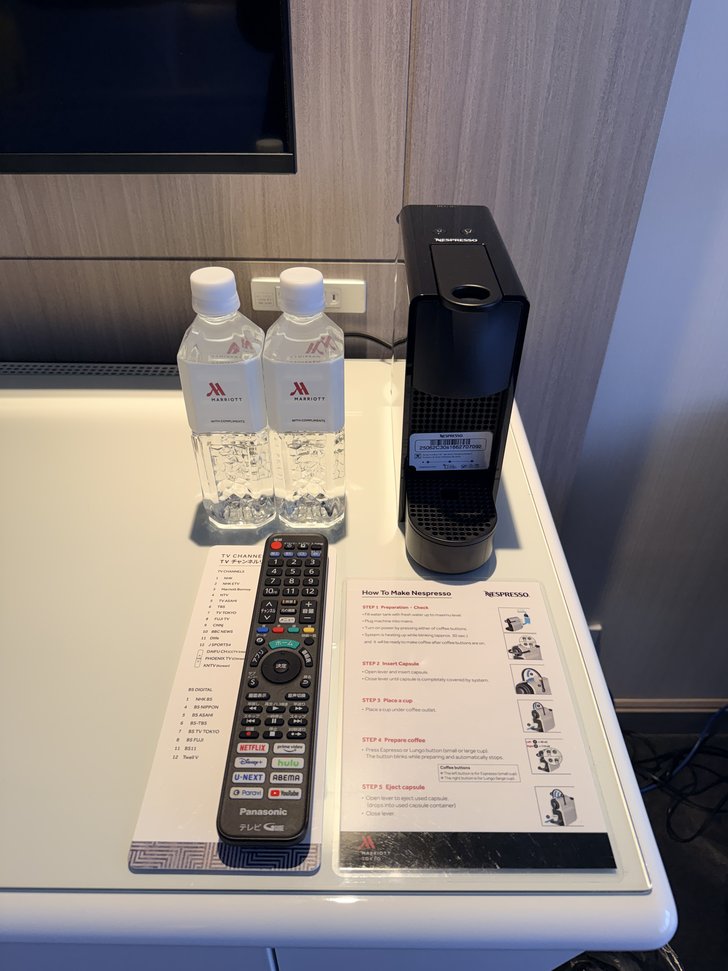 テーブル上の水2本とコーヒーマシン、テレビリモコン