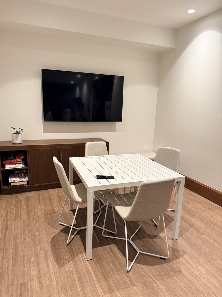 白いテーブルと椅子、壁掛けテレビのある部屋